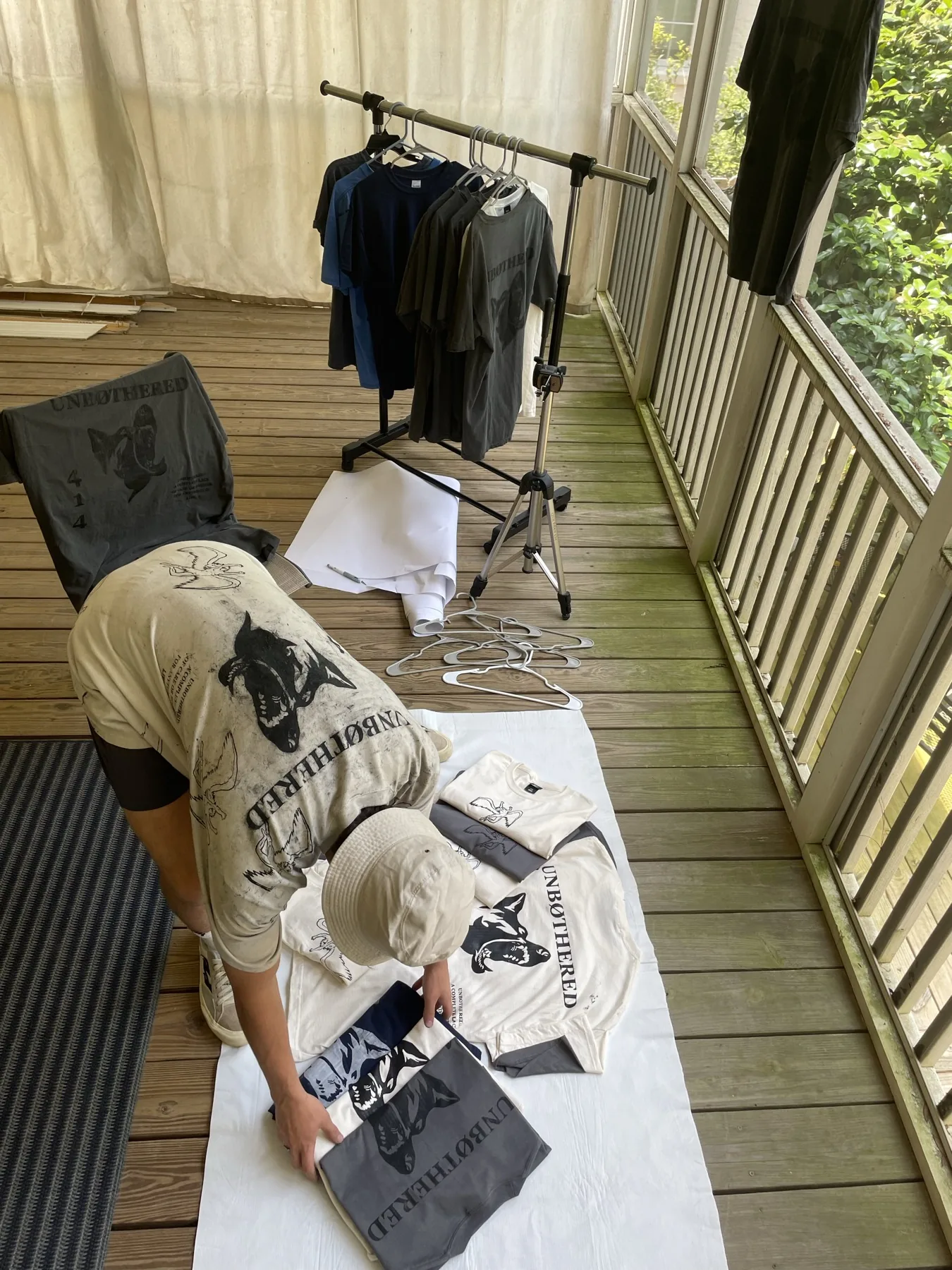 Arranging printed Stitches and 808s tees in the original screen-porch workspace